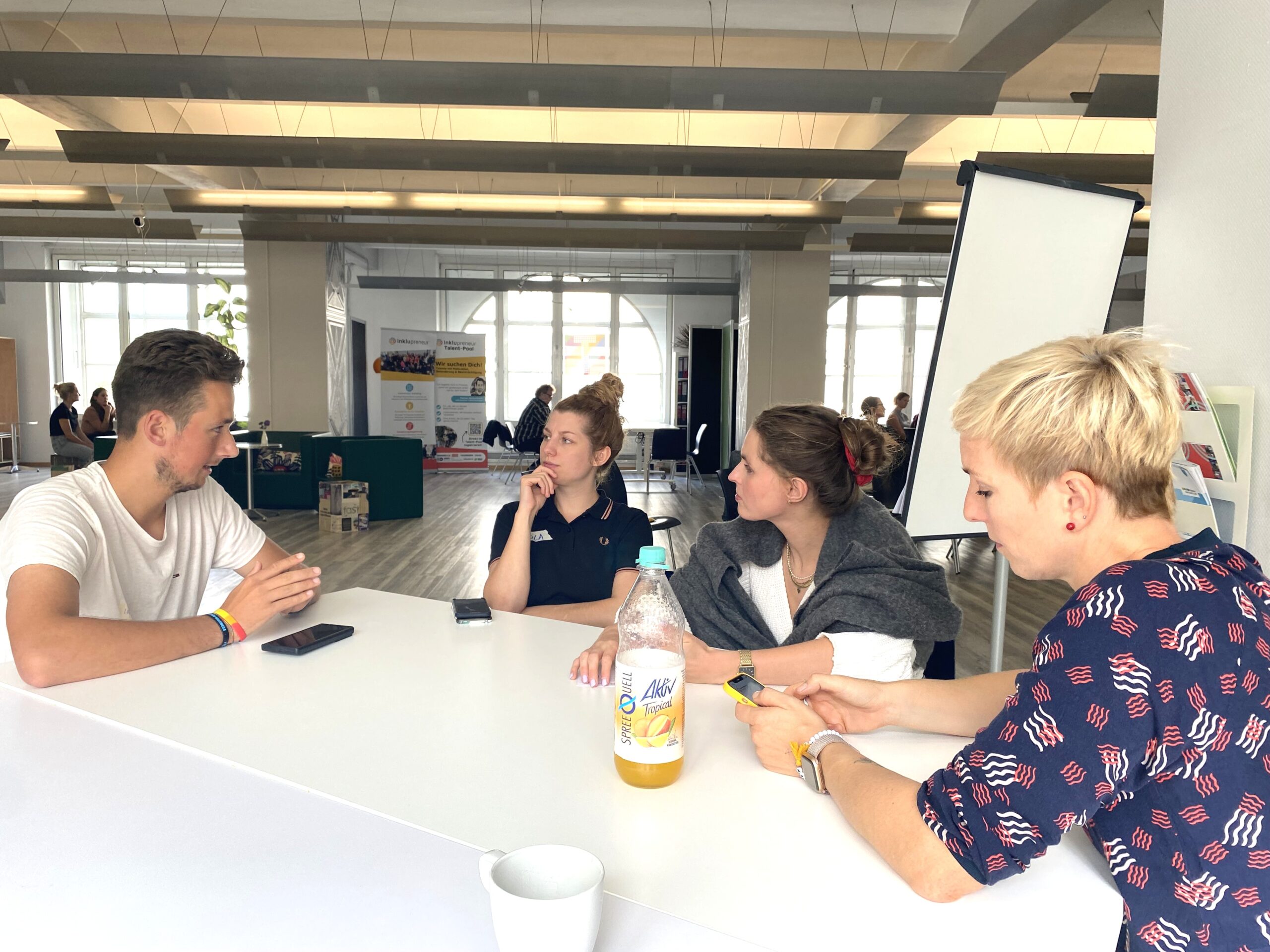 Inklupreneur Mentor Louis im Gespräch mit Teilnehmenden am Tisch.